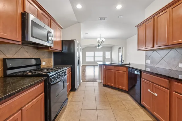 a large kitchen with stainless steel appliances granite countertop a stove top oven a sink dishwasher a refrigerator and cabinets with wooden floor