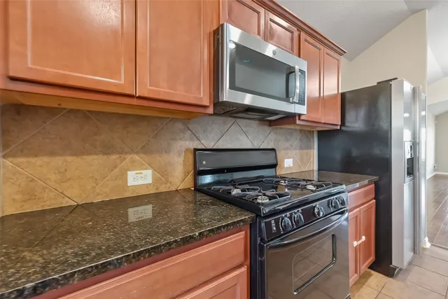 a kitchen with stainless steel appliances granite countertop a stove microwave and refrigerator