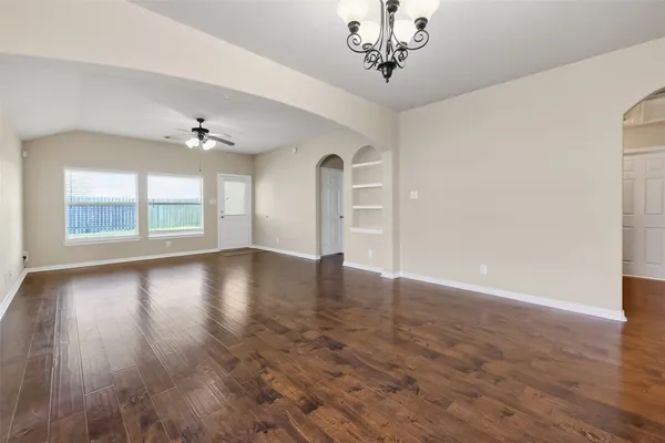 a view of an empty room with a window and wooden floor