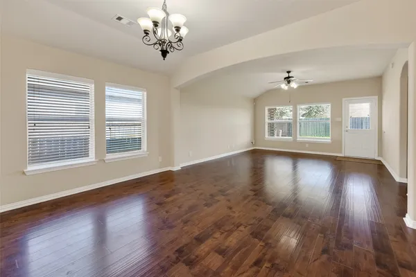 a view of an empty room with wooden floor and a window