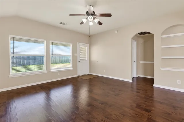 a view of an empty room with window and wooden floor