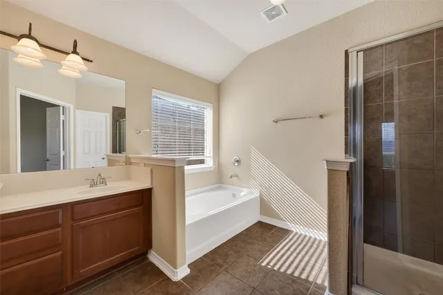 a spacious bathroom with a bathtub double sink shower and a mirror