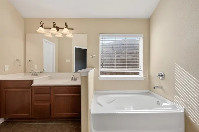 a bathroom with a tub sink and mirror
