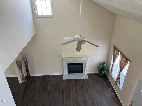 an empty room with wooden floor fireplace and staircase
