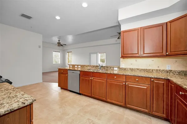 a large kitchen with granite countertop a sink and dishwasher stove with wooden cabinets