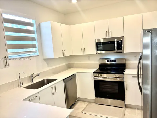 a kitchen with stainless steel appliances a stove a sink and a microwave