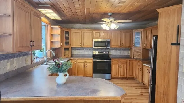 a kitchen with stainless steel appliances kitchen island granite countertop a refrigerator a stove a sink dishwasher and microwave with wooden floor
