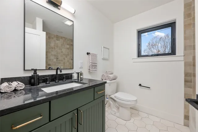 a bathroom with a granite countertop toilet a sink and a mirror