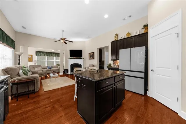 a living room with stainless steel appliances granite countertop furniture wooden floor and a view of kitchen
