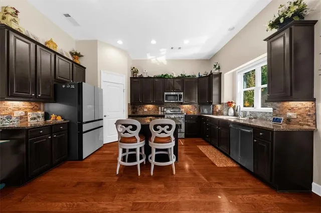 a kitchen with stainless steel appliances granite countertop a table chairs sink refrigerator and cabinets