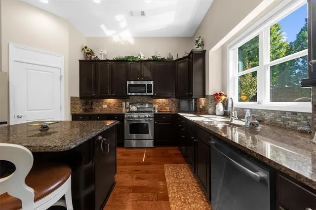 a kitchen with stainless steel appliances granite countertop a sink stove and refrigerator