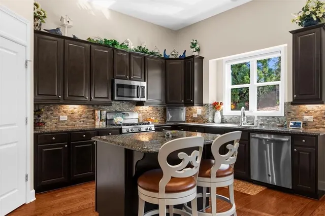 a kitchen with kitchen island granite countertop wooden cabinets and a refrigerator