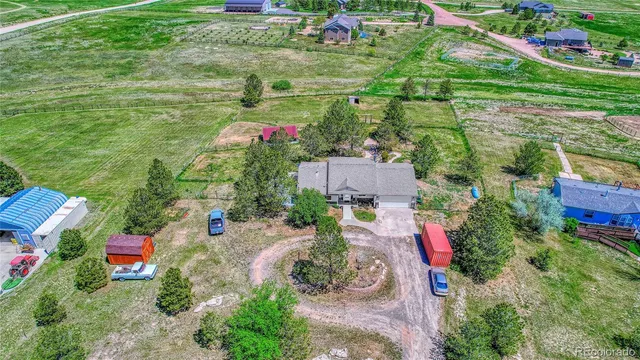 an aerial view of residential house with outdoor space and trees all around