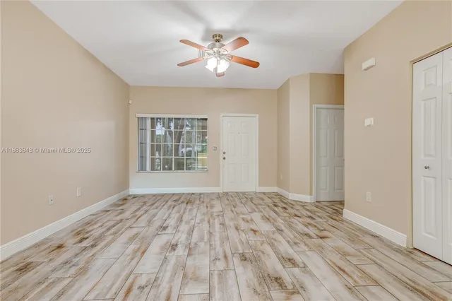 a view of empty room with wooden floor and fan