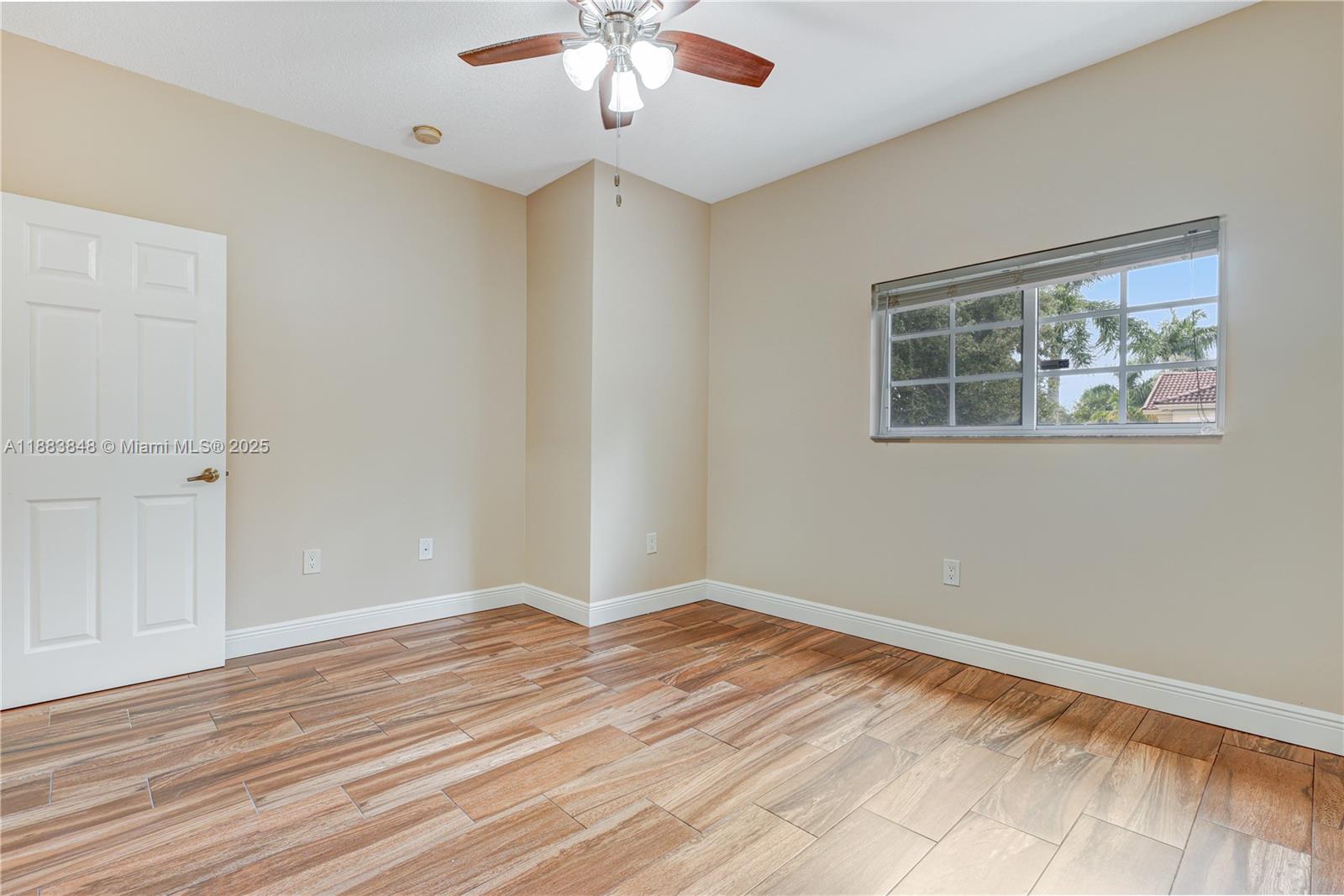 7627 East Stonecreek Circle Davie, FL 33024 - Photo 21 of 29 an empty room with wooden floor chandelier fan and windows