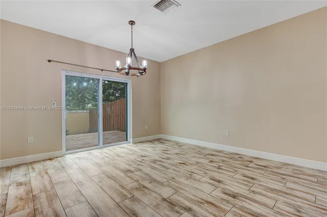 a view of a livingroom with a chandelier fan and wooden floor