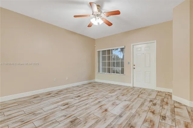a view of empty room with wooden floor and fan