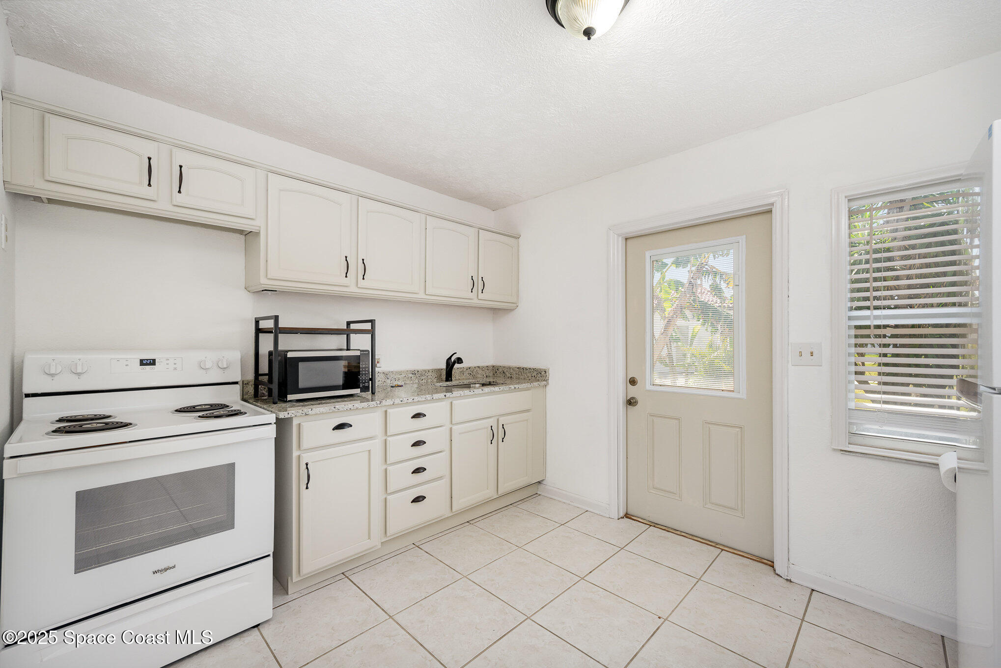 121 Del Flora Indialantic, FL 32903 - Photo 7 of 15 a kitchen with white cabinets and white appliances