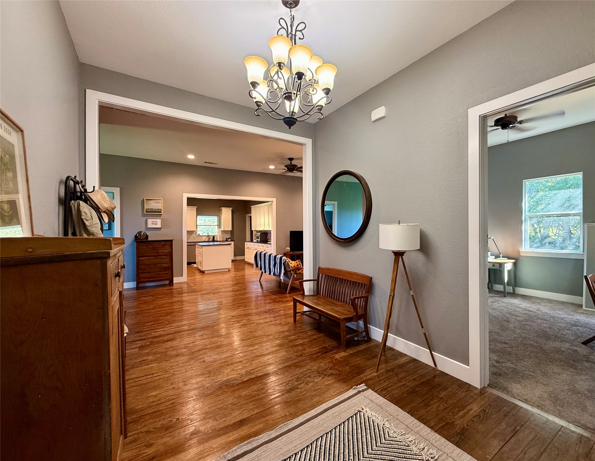 739 Pleasant Grove Road Elgin, TX 78621 - Photo 5 of 29 Interior hallway featuring wood-finish flooring, a decorative chandelier, and light gray wall paint
