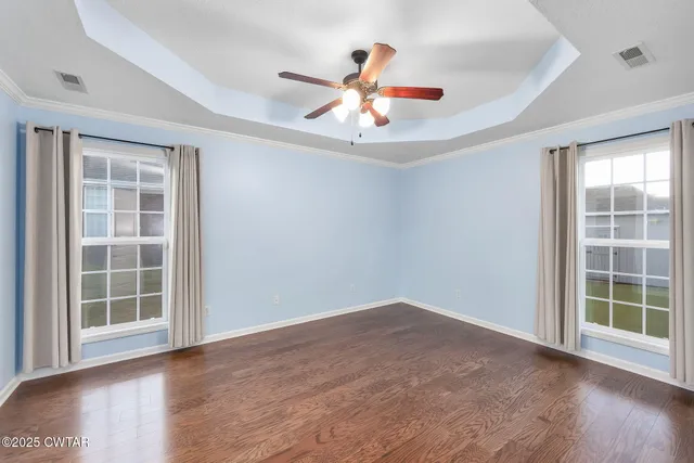 an empty room with wooden floor cabinet and windows