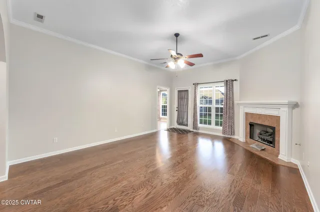 a view of an empty room with wooden floor fireplace and a window