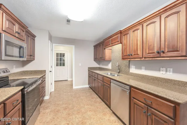 a kitchen with stainless steel appliances granite countertop a stove sink and cabinets