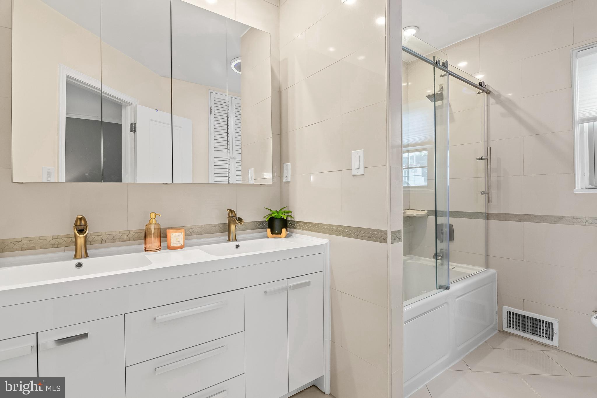 3302 Northbrook Road Pikesville, MD 21208 - Photo 24 of 45 a bathroom with a double vanity sink a mirror and a bathtub