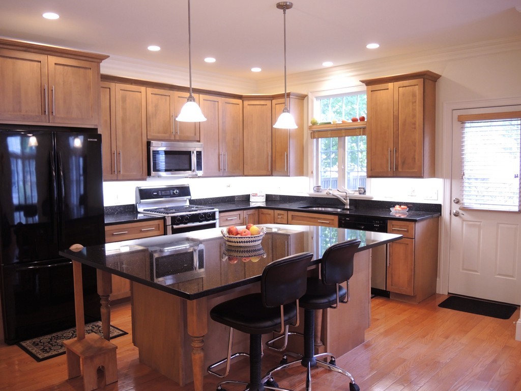 38 Maple Street, Unit 2 Needham, MA 02492 - Photo 6 of 26 a kitchen with kitchen island granite countertop a sink a center island stainless steel appliances cabinets and a window