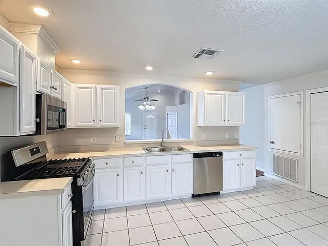 a kitchen with white cabinets appliances and a sink