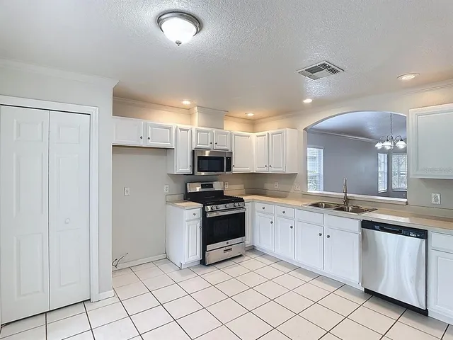 a kitchen with white cabinets a sink and white appliances