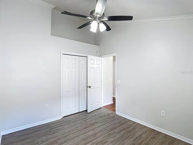 a view of an empty room with window a ceiling fan and wooden floor