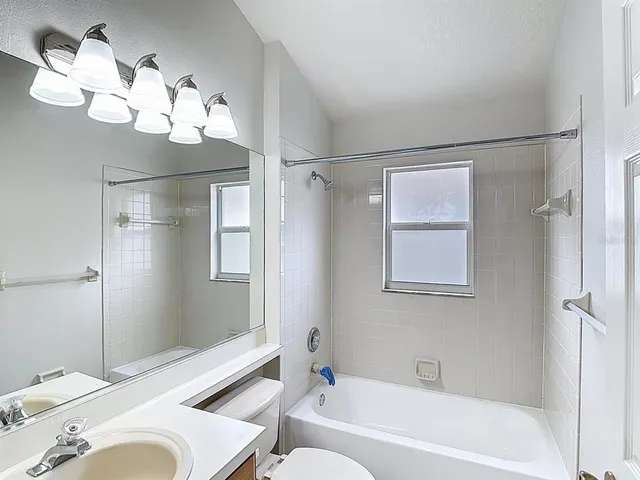 a bathroom with a sink a toilet a mirror a bathtub and shower