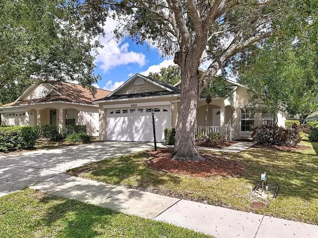 a front view of a house with a garden and trees