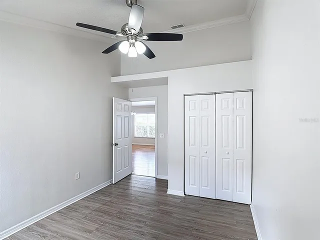 wooden floor in an empty room with a chandelier fan