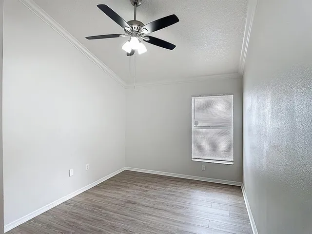 an empty room with wooden floor chandelier fan and windows