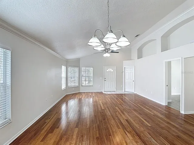 a view of a livingroom with a large window wooden floor and chandelier