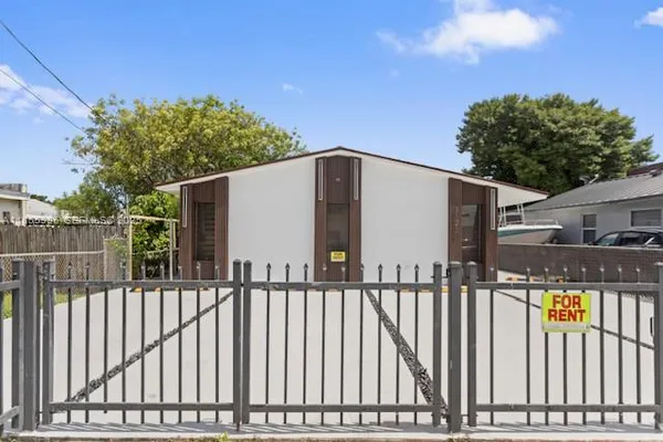 a view of a house with a small yard and wooden fence