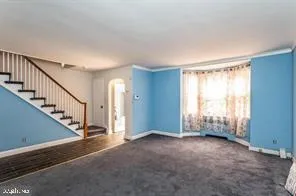 a view of an empty room with wooden floor and stairs
