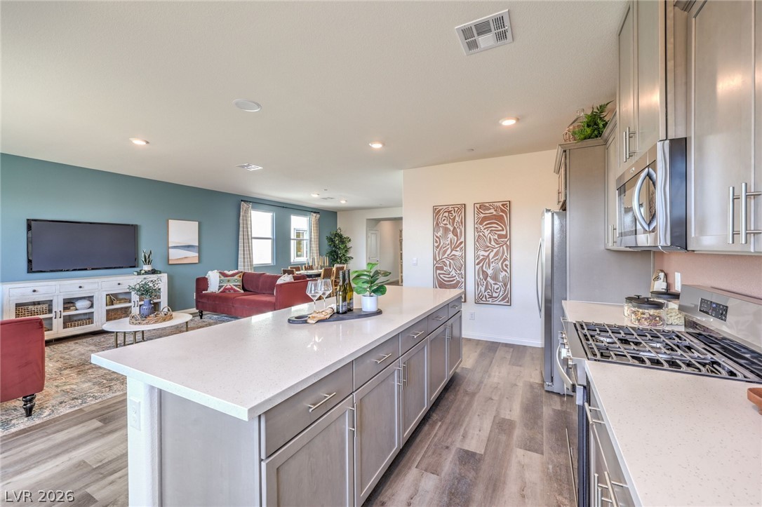 1017 Copper Robin Street Henderson, NV 89011 - Photo 42 of 43 Kitchen with stainless steel appliances, open floor plan, gray cabinets, light countertops, and light wood finished floors. Photo is representational only; actual home finishes may vary.