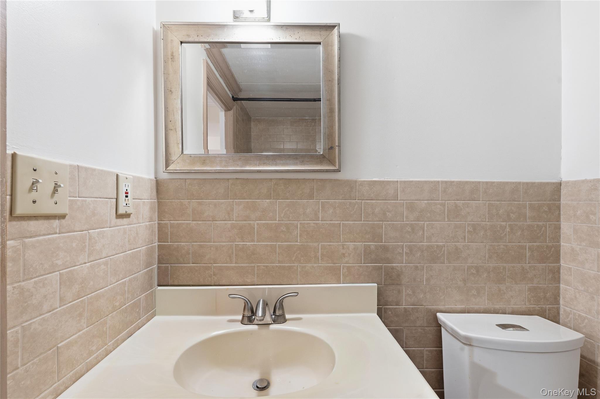 863 Home Street Bronx, NY 10459 - Photo 9 of 46 a bathroom with a sink a toilet and a mirror