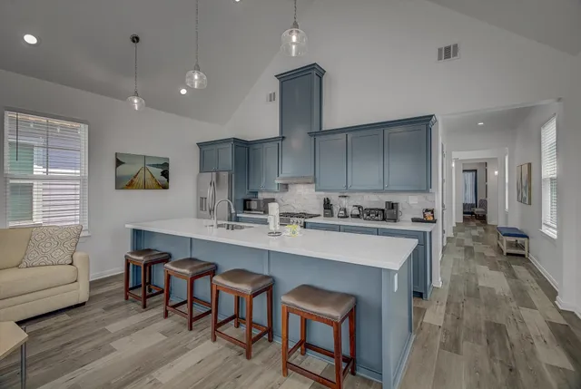 a large kitchen with kitchen island a stove a sink a refrigerator and wooden floor