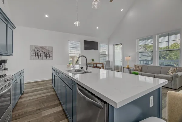a living room with stainless steel appliances kitchen island granite countertop a couch cabinets and a window