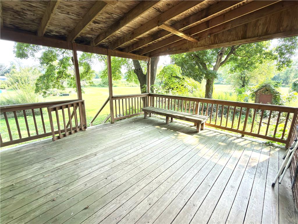 4550 Vera Cruz Road Center Valley, PA 18034 - Photo 8 of 43 An expansive covered wooden deck looks out over a grassy yard bordered by mature trees.