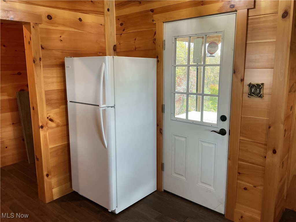 10550 Symmes Creek Road Adamsville, OH 43802 - Photo 13 of 21 Kitchen with freestanding refrigerator, wood walls, and dark wood-type flooring
