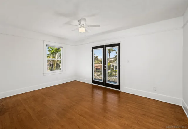 a view of an empty room with a window and wooden floor