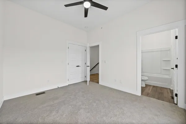 a view of a hallway with wooden floor and a bathroom