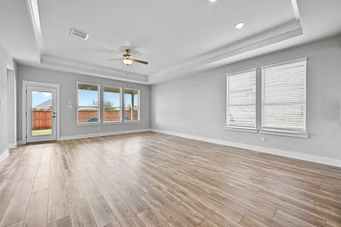 a view of an empty room with a window and wooden floor