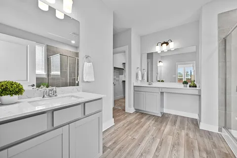 a large white kitchen with a sink dishwasher a stove and white cabinets with wooden floor