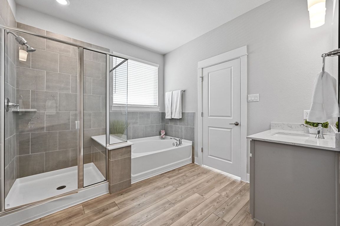 284 Grace Lilly Drive Buda, TX 78610 - Photo 22 of 40 Full bath featuring a garden tub, a stall shower, double vanity, and luxury vinyl floors
