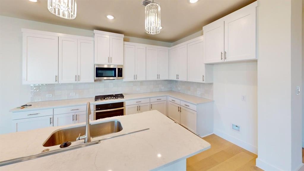 7013 Lathrop Lane Frisco, TX 75033 - Photo 4 of 26 Kitchen with tasteful backsplash, white cabinets, and light wood finished floors